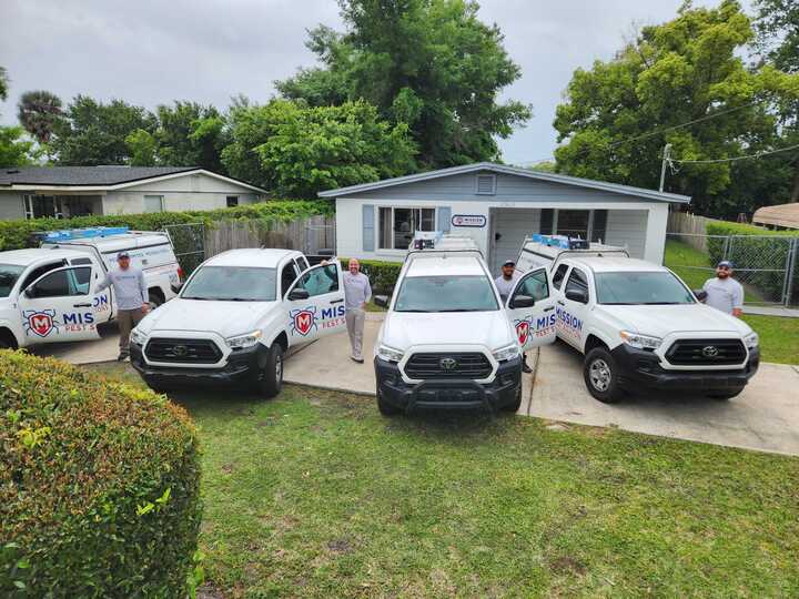 Mission Pest Solutions Team Members standing outside of their pest control vehicles